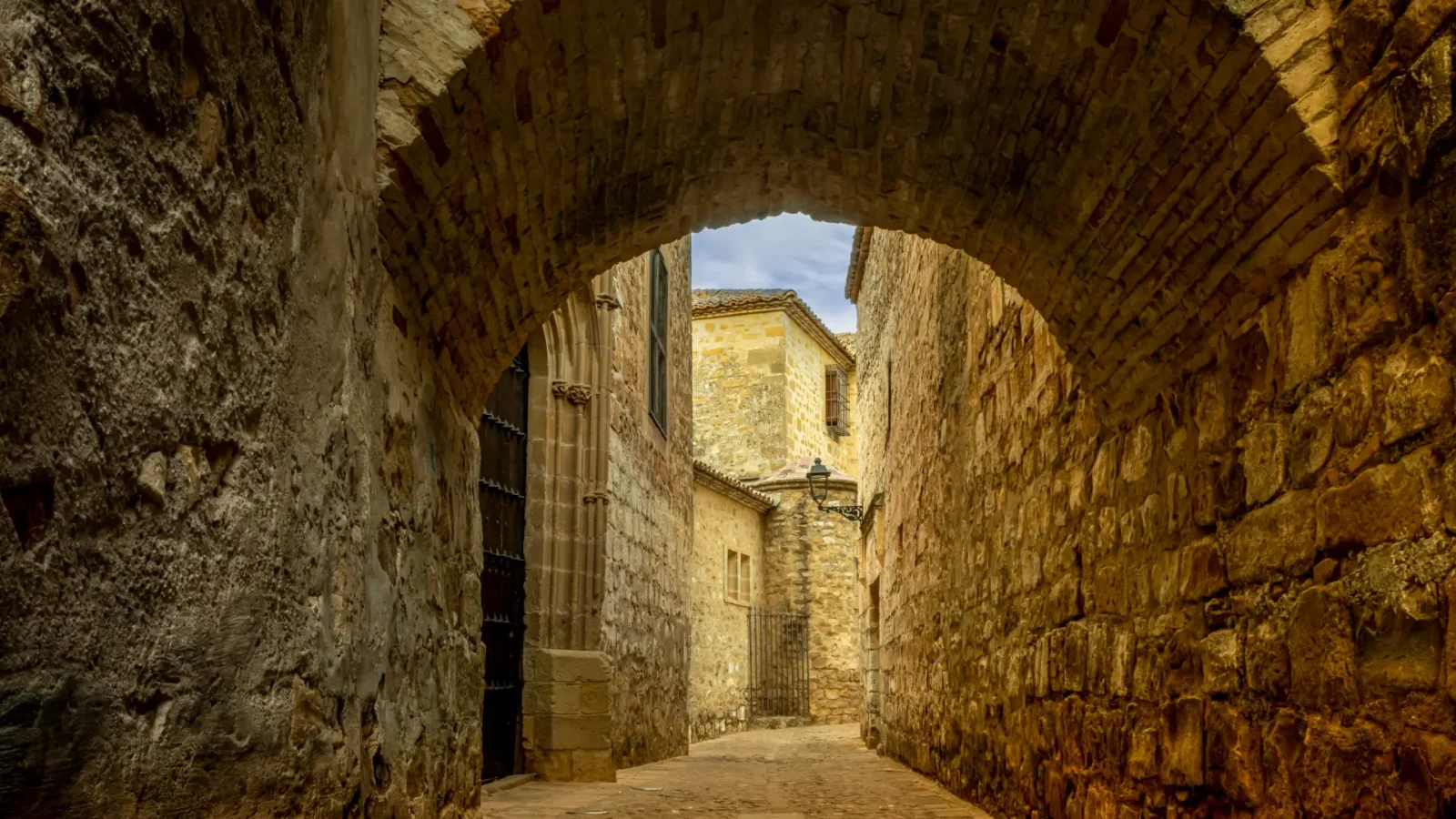 A stone archway into the old town at dusk in Baeza, Jaén, Andalucía, Spain