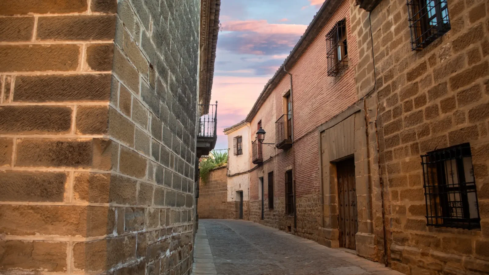 A quiet street of golden-stone houses at dusk in Baeza, Jaén, Andalucía, Spain