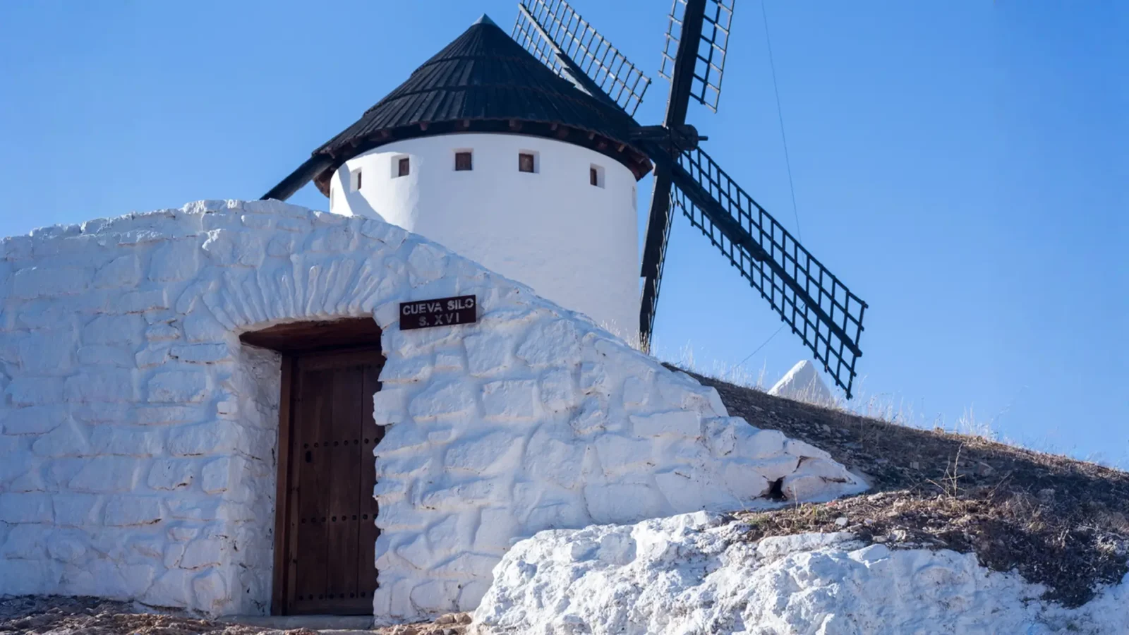 A 16th-century whitewashed cave-silo below a windmill in Campo de Criptana, Ciudad Real, Spain