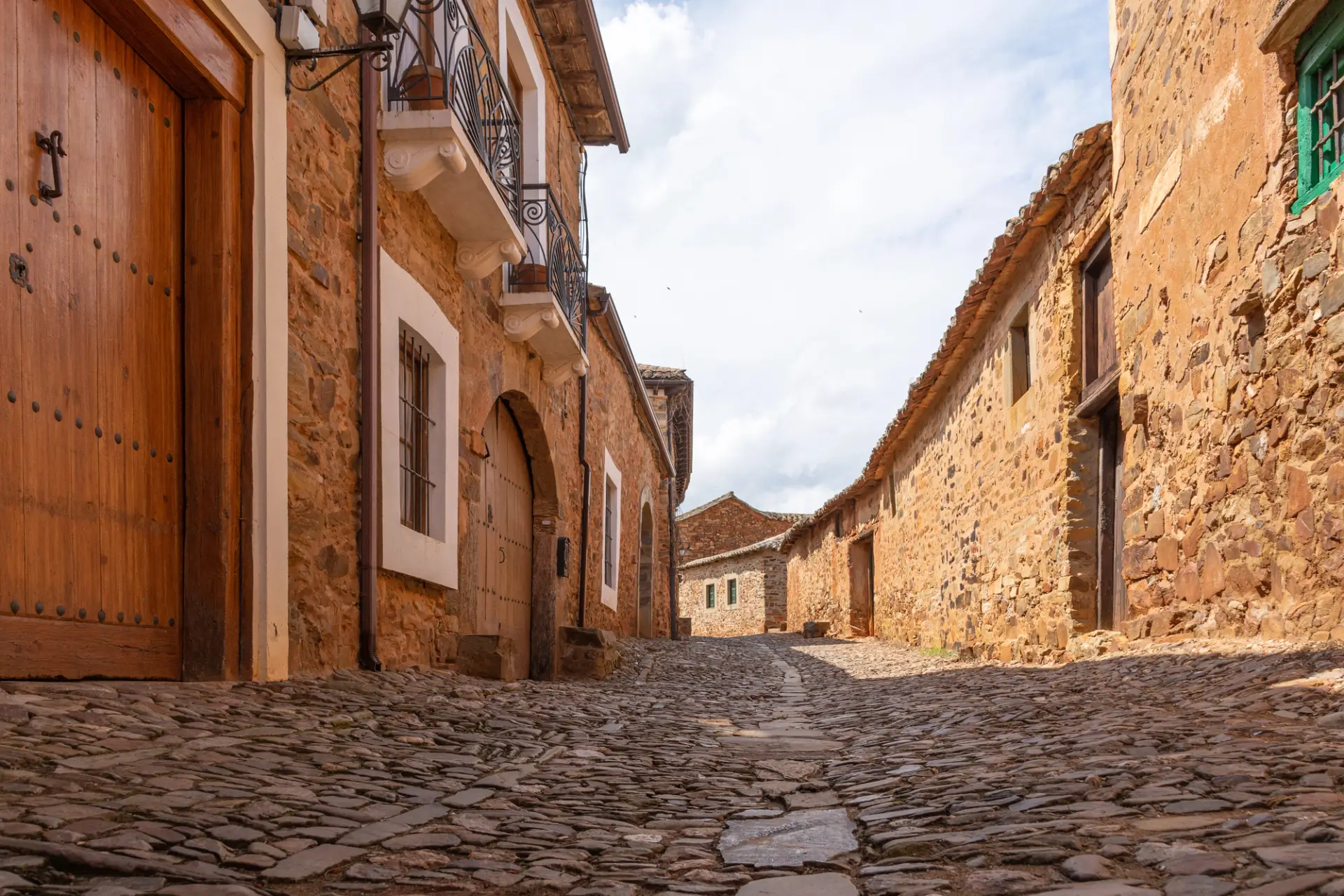 Empty cobbled street lined with red-stone houses in Castrillo de los Polvazares, a historic village in León