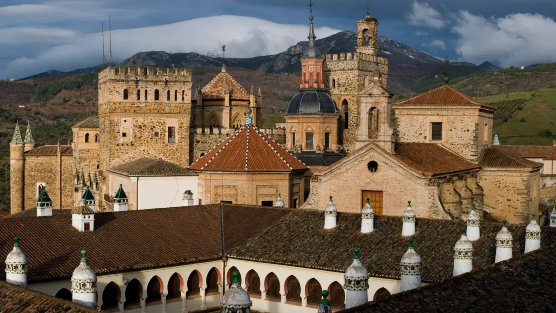 The fortified Royal Monastery of Guadalupe rising above the village against the Villuercas mountains, Extremadura, Spain