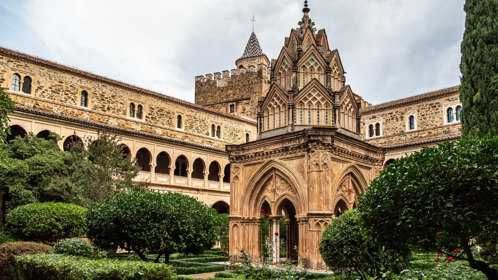Mudejar cloister of the Royal Monastery of Guadalupe, a stone courtyard with a Gothic templete and gardens, Extremadura, Spain
