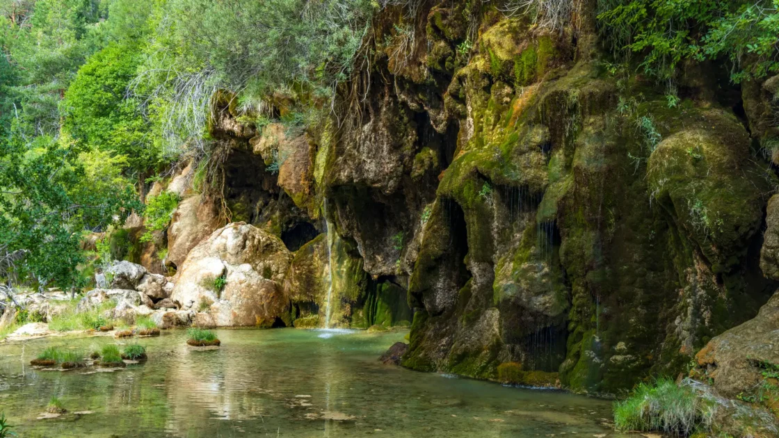 A waterfall above the cave mouth at the spring of the Cuervo river (Nacimiento del Río Cuervo) near Vega del Codorno, Castilla-La Mancha, Spain