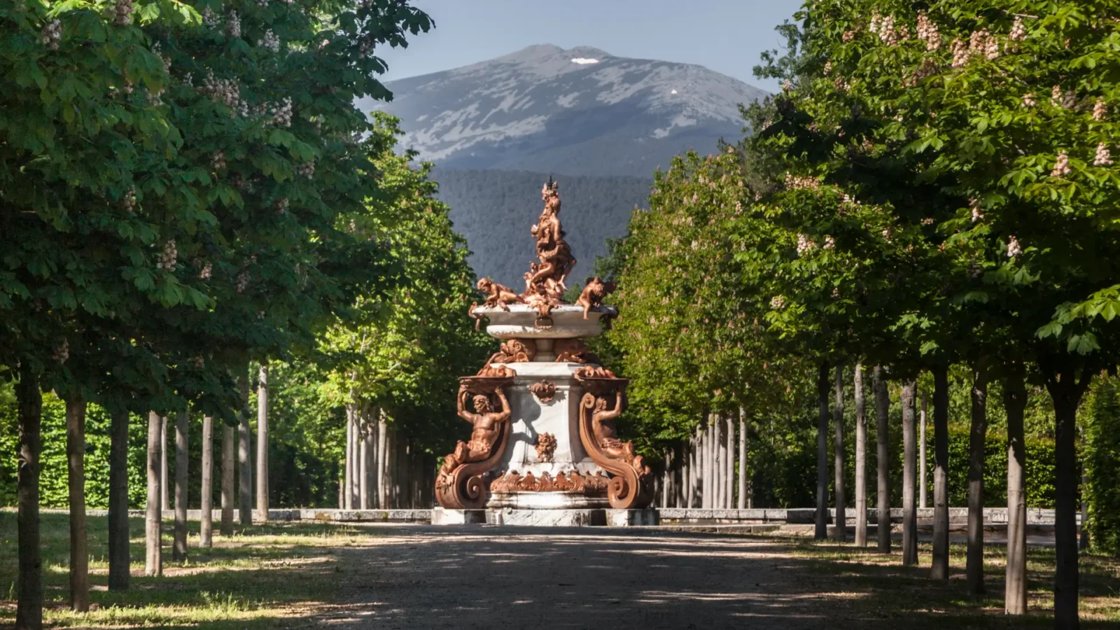 A tree-lined garden avenue and fountain below the Sierra de Guadarrama at La Granja de San Ildefonso, Castilla y León, Spain