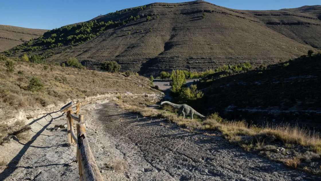 Dinosaur trackway with a model dinosaur beside the walkway near Enciso, La Rioja, Spain