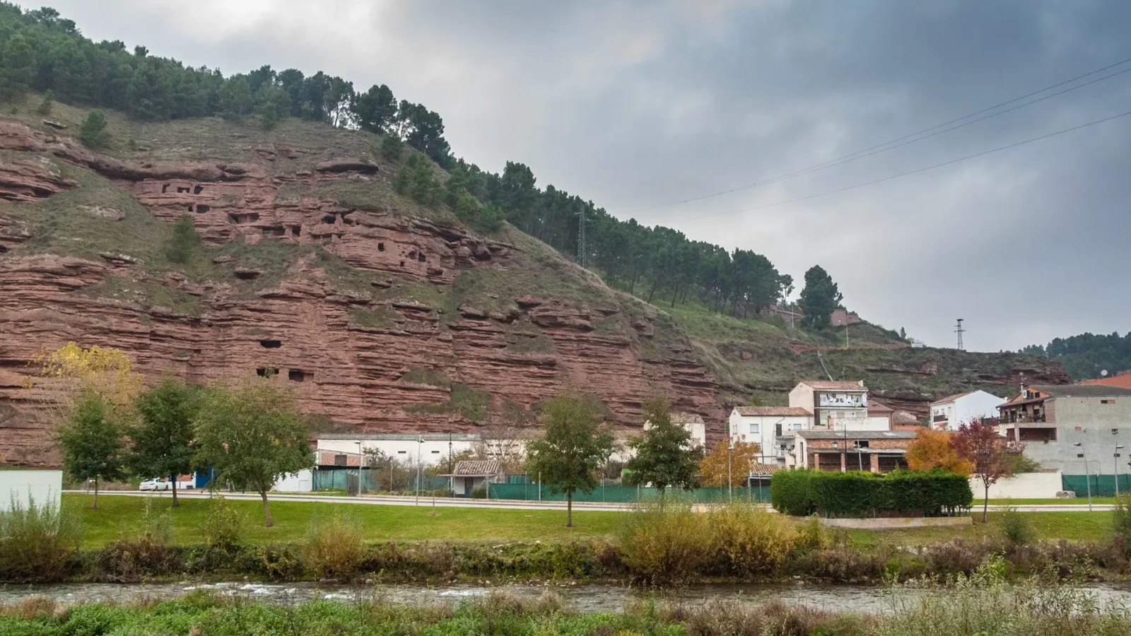 Rows of man-made caves carved into the red cliffs above the river at Nájera, La Rioja, Spain
