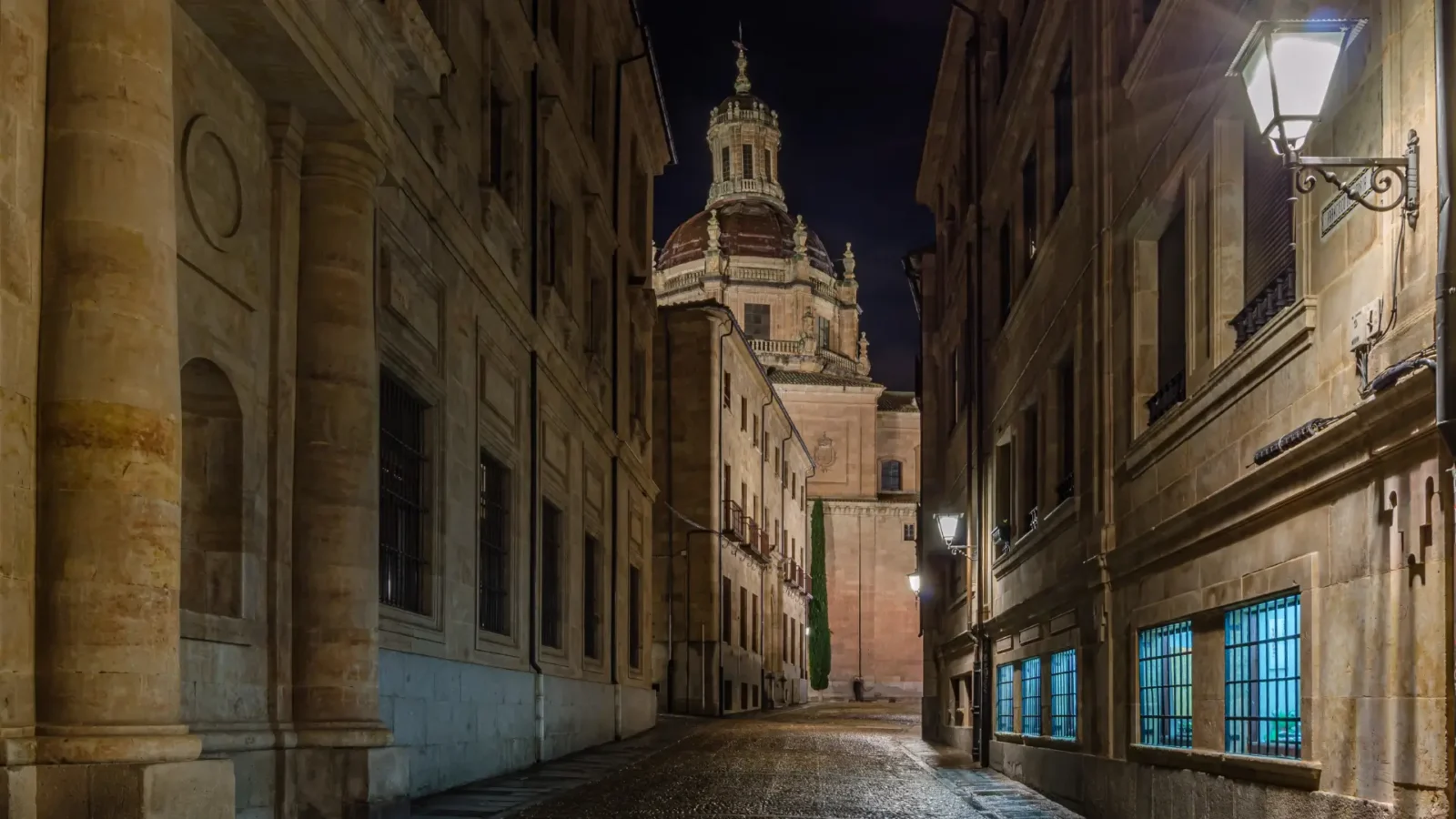 A lamplit golden-stone lane in Salamanca's old town at night, Castilla y León, Spain