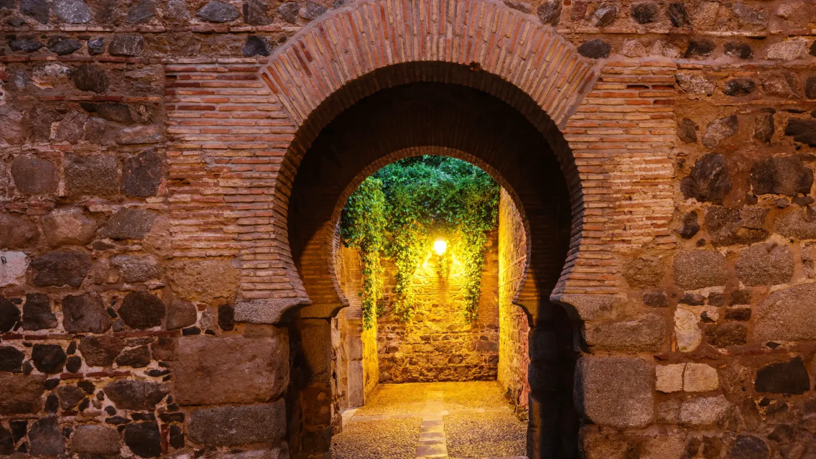 A lamplit horseshoe archway in the old town of Toledo, Castilla-La Mancha, Spain