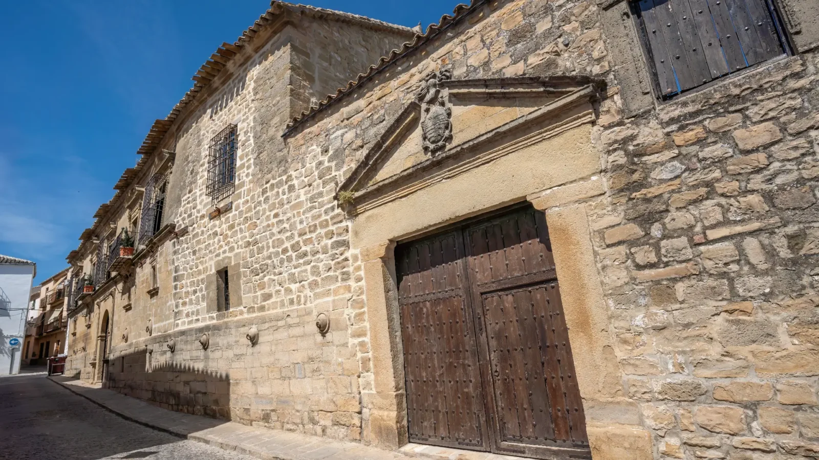 Wooden doorway in a golden-stone Renaissance façade in Úbeda, Andalucía, Spain