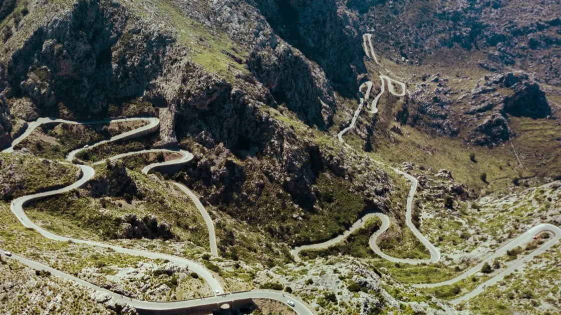Aerial view of a winding mountain road curving through rugged Spanish hills