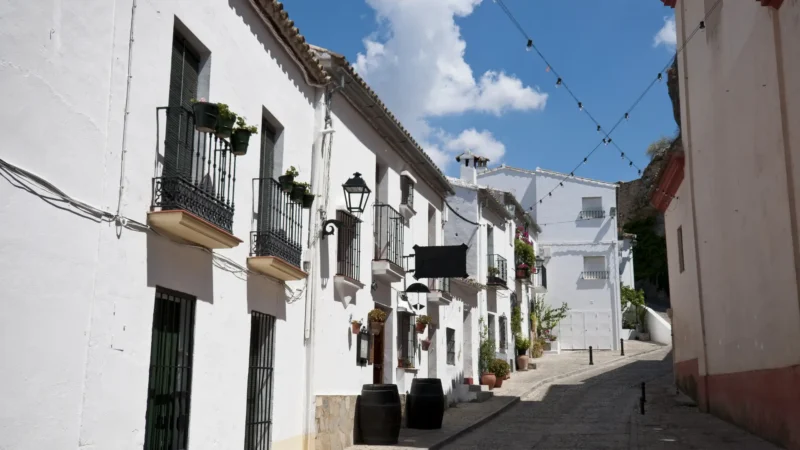 A whitewashed street with flower-filled balconies in the old town of Zahara de la Sierra, Cádiz, Andalucía, Spain